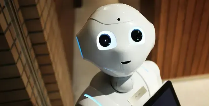 A white humanoid robot with large black eyes and a small mouth looks forward.