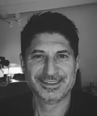 Black and white headshot of a smiling man with short dark hair and a beard.