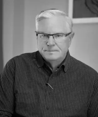 Black and white portrait of an older man with glasses and a striped shirt.