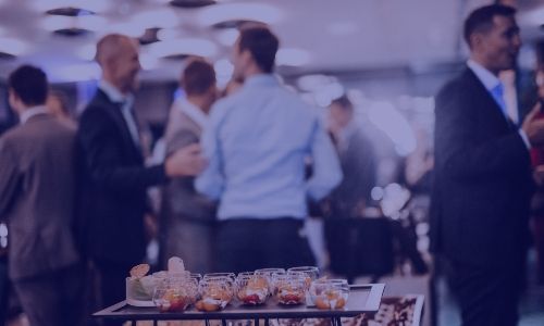 Professionals gathered at a social event with drinks on a table.