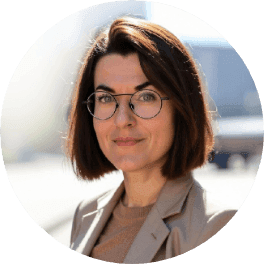 A professional woman with short dark hair and glasses smiles faintly at the camera.