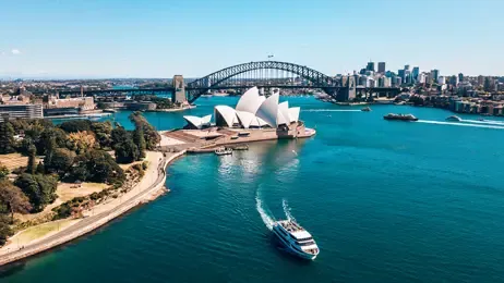 Aerial view of Sydney Opera House, Harbour Bridge, and city skyline on a sunny day.