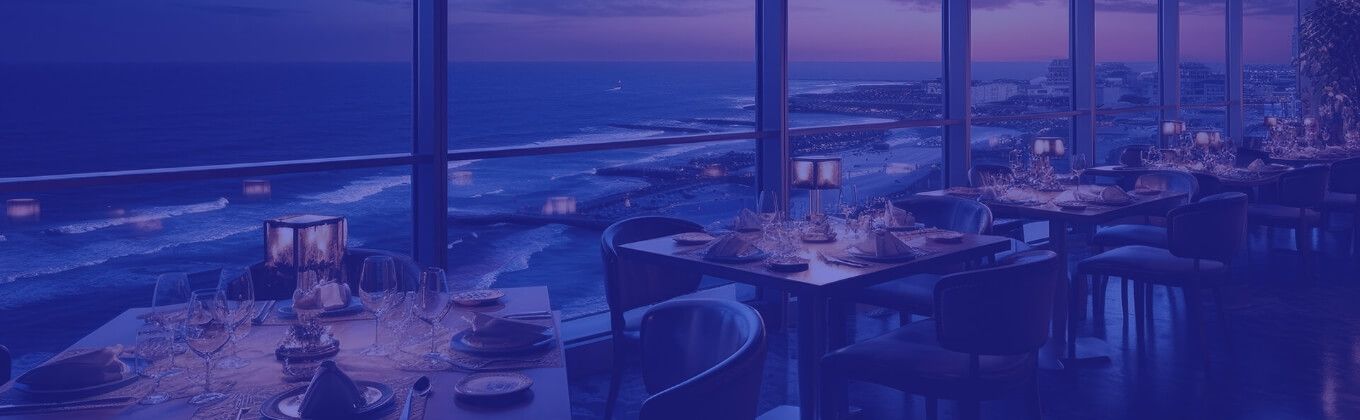 Elegant restaurant interior with dining tables overlooking a beautiful ocean view at twilight.