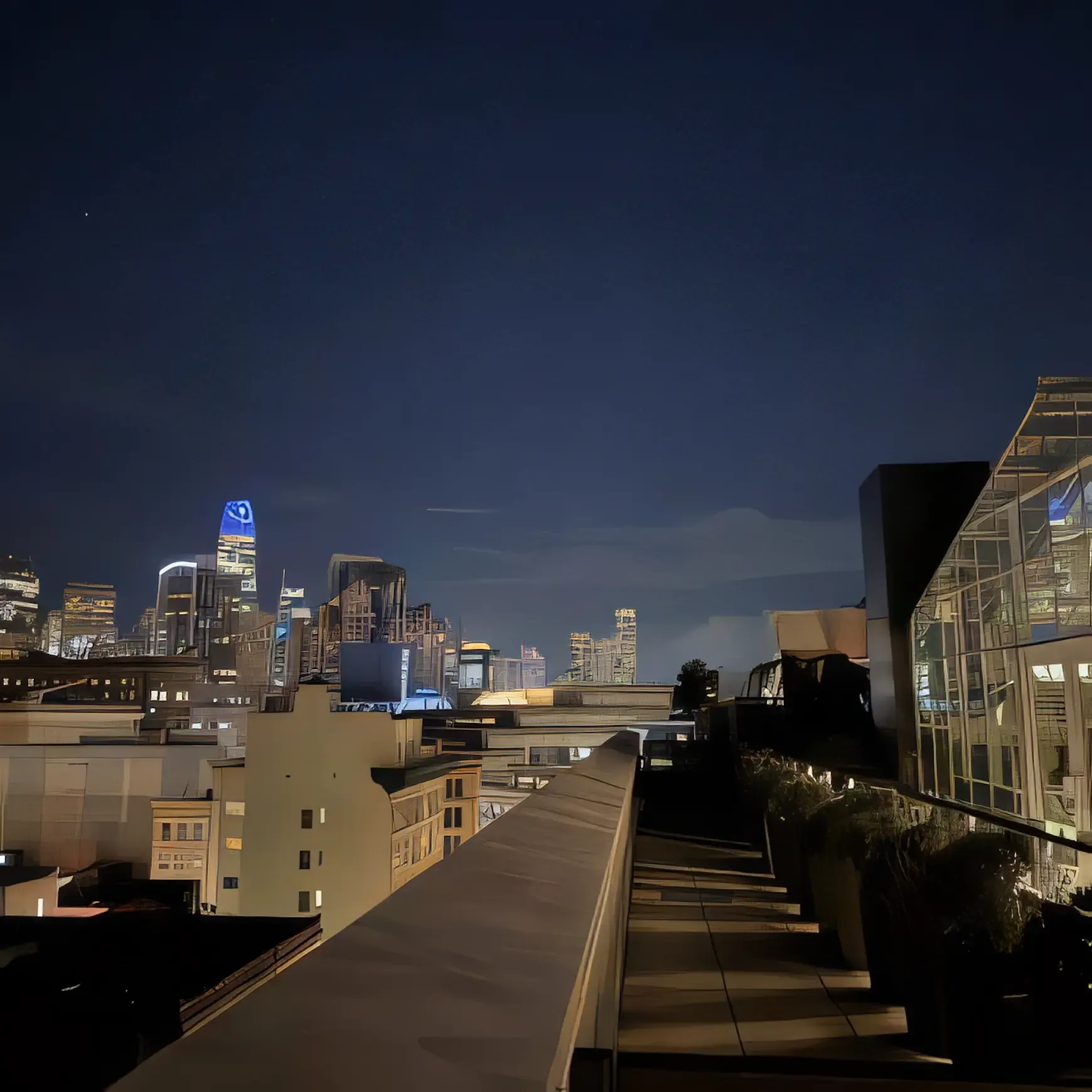 Night view of a city skyline with illuminated skyscrapers and dark sky.