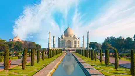 The pristine white marble Taj Mahal stands majestically with a long reflecting pool and gardens.