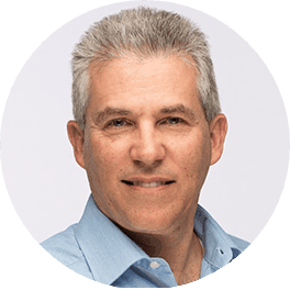 Smiling man with graying hair in a light blue shirt looking forward.