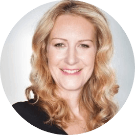 Smiling woman with blonde wavy hair looking directly at the camera.