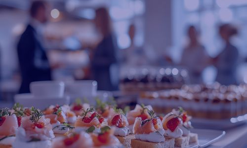 Close-up of a catering spread with salmon canapés and pastries at a corporate event.