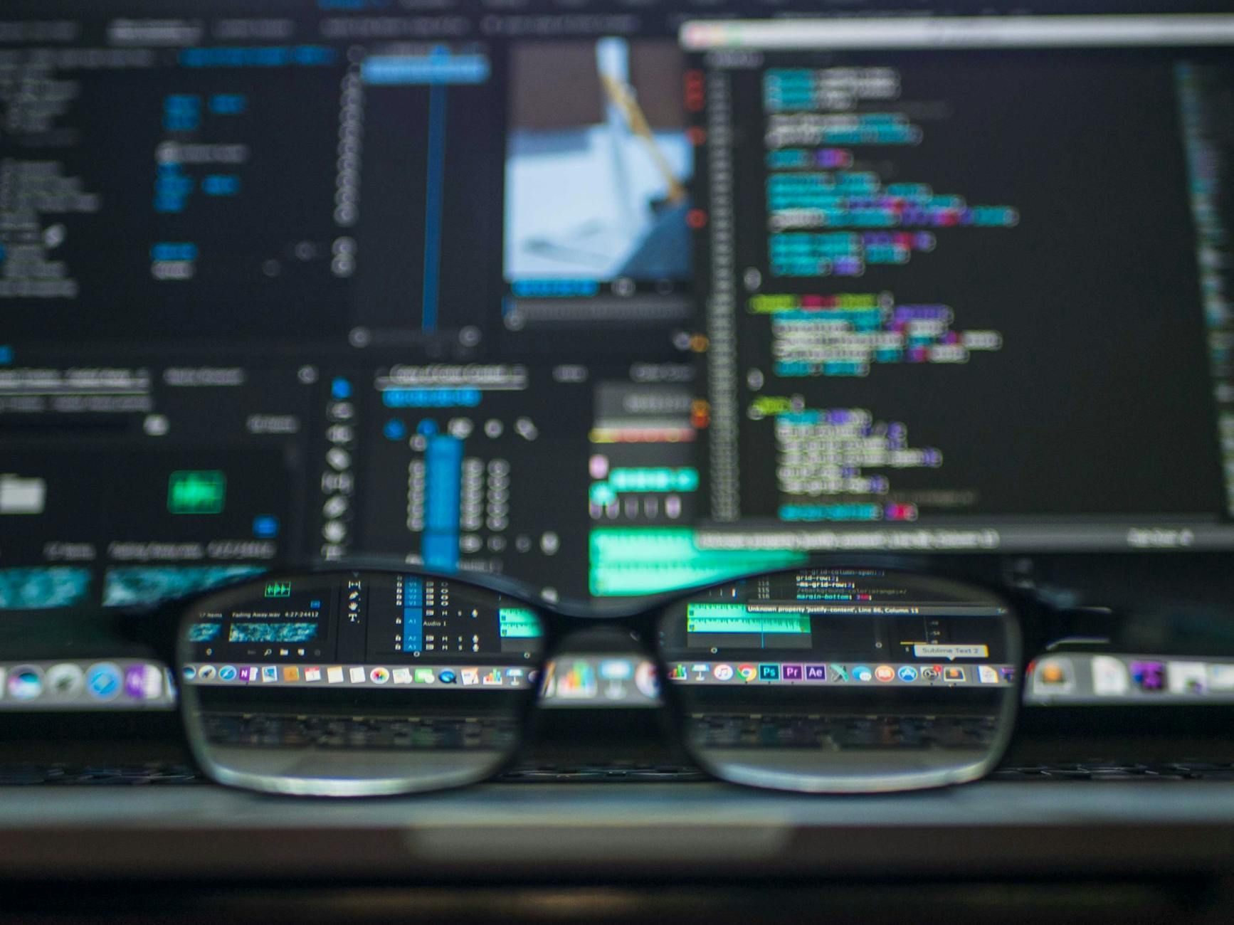 Glasses reflecting lines of code on a laptop screen, suggesting programming work.