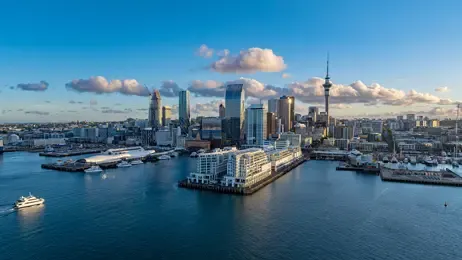 Auckland skyline with the Sky Tower, modern buildings, and harbor with boats.