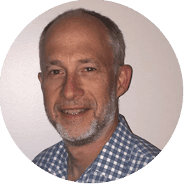 Headshot of a smiling middle-aged man with a beard wearing a checkered shirt.