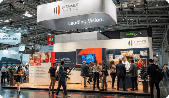 People gather and network at the busy STEMMER IMAGING booth with 'Leading Vision' signage.