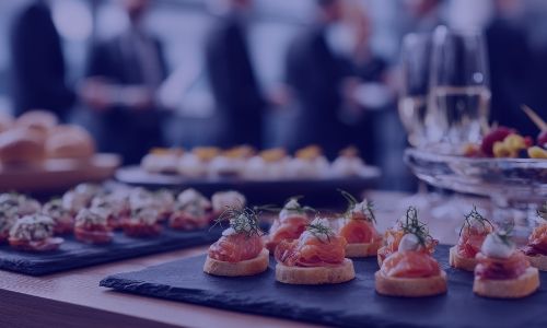 Elegant buffet table with salmon canapés and other appetizers at a professional event.