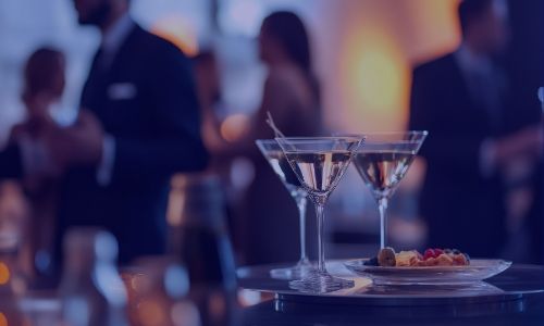 Two martini glasses and appetizers on a tray at an elegant evening event.